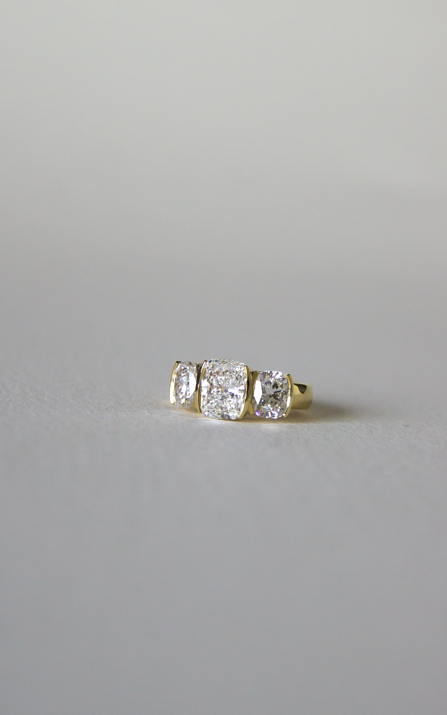 Fine jewellery three-stone diamond ring in 18K yellow gold with rectangular cushion-cut diamonds and half-bezel colonnade design