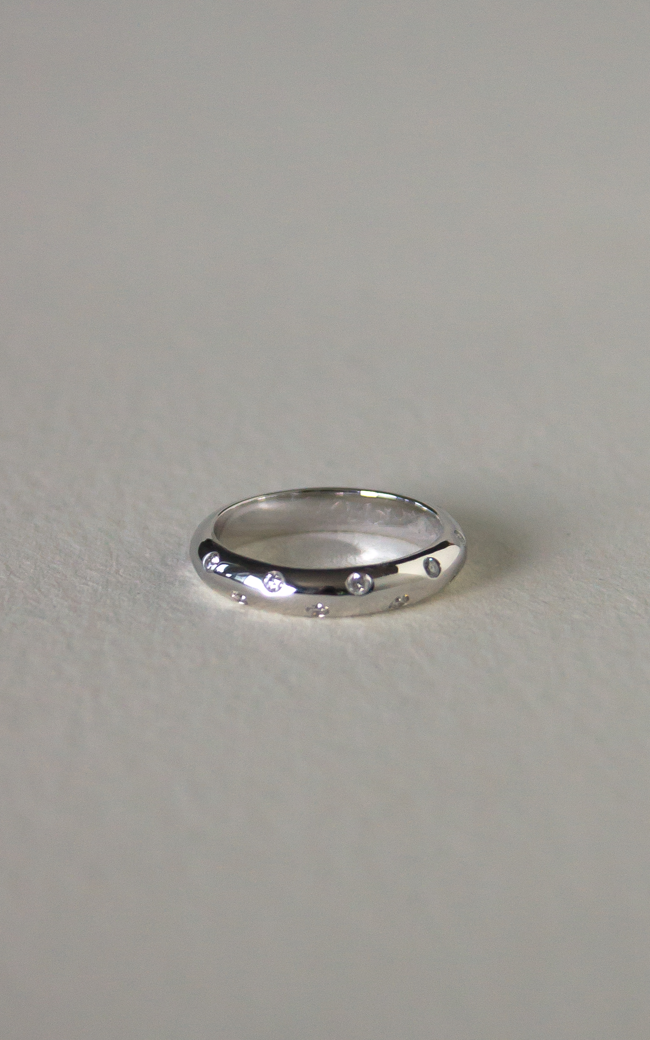 Facet Arc Diamond Band in 18k white gold featuring 13 scatter-set round brilliant-cut diamonds along a hammered band